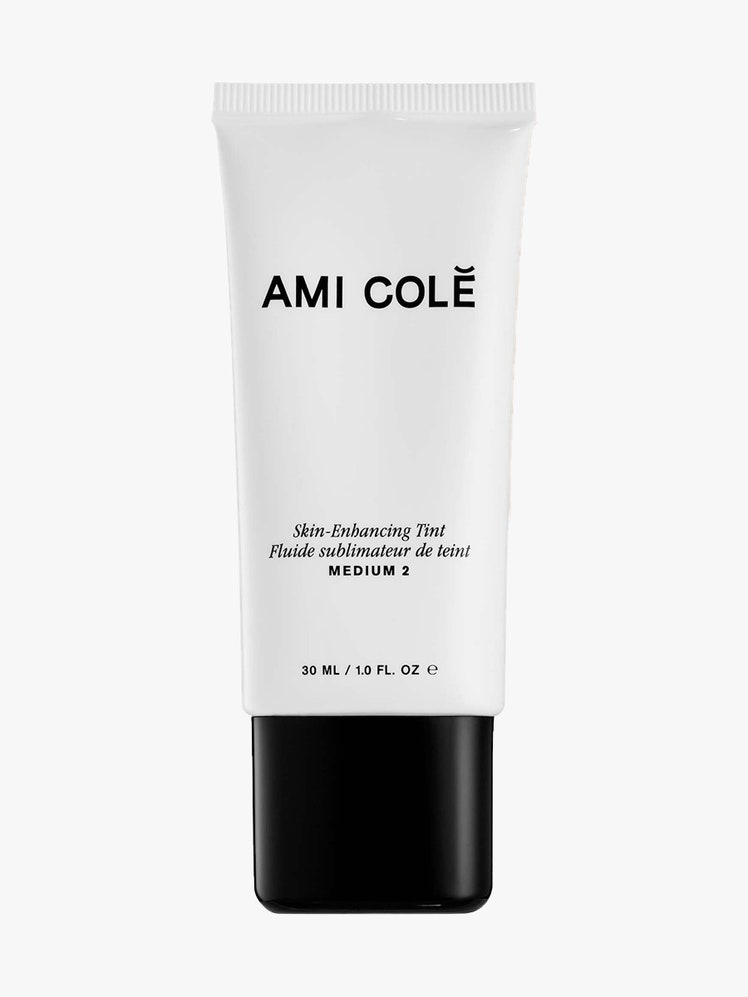 Ami Colé Skin Enhancing Tint white tube with black cap on light gray background