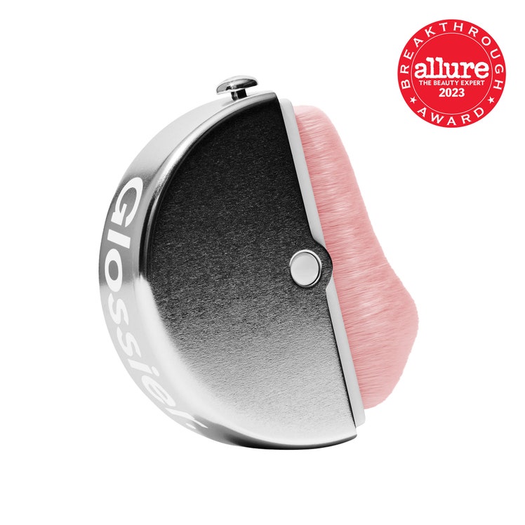 Glossier Stretch Face Brush light pink face brush in round silver case on white background with red Allure BoB seal in...