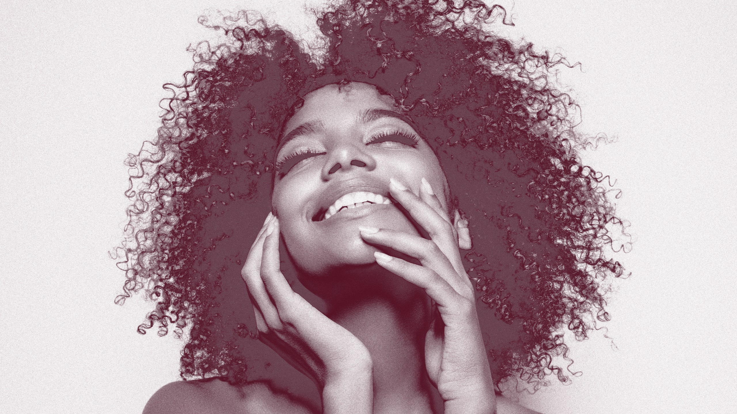 black and white photo of a black woman with natural hair smiling and holding her face