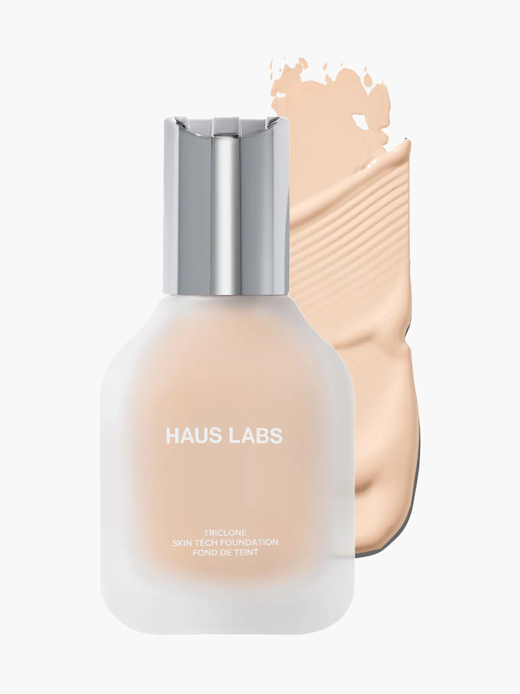 Triclone Skin Tech Foundation in branded clear bottle with silver cap on top of product swatch on light gray background